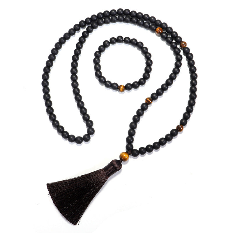 Black beaded necklace with a tassel on a white background