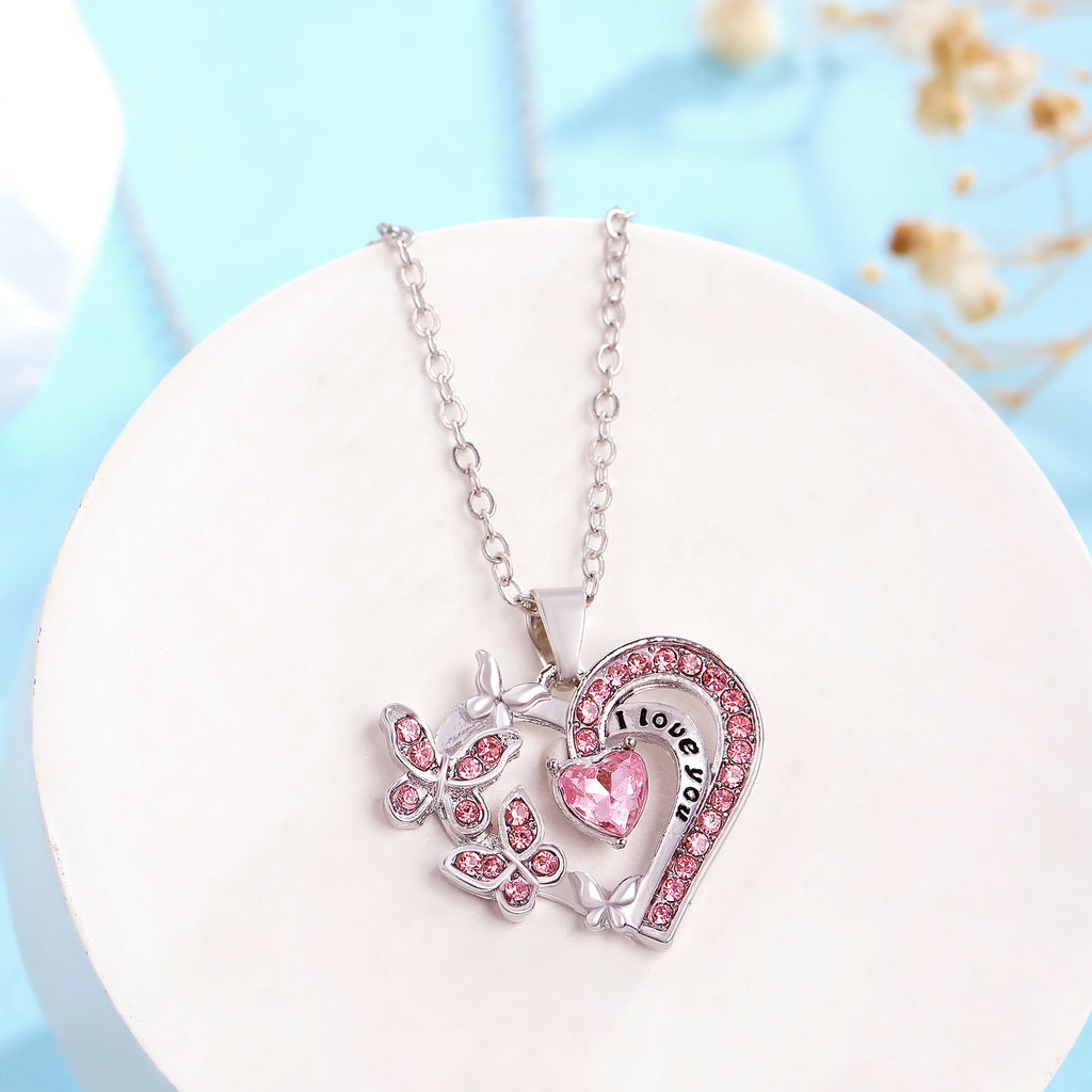 Necklace with pink heart and butterfly pendant on a white stand with a light blue background