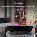 Fog diffuser with building model on a desk, emitting mist.