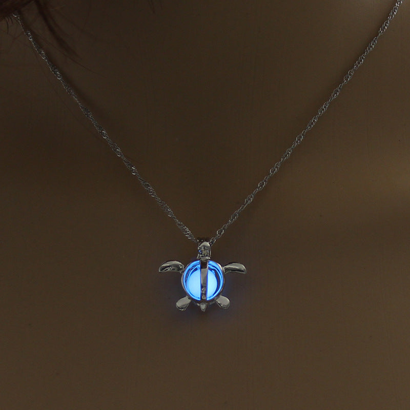 Necklace with a turtle-shaped pendant that glows blue on a dark background