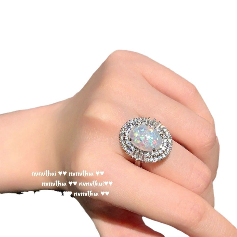 Ring with a colorful gemstone on a hand against a white background