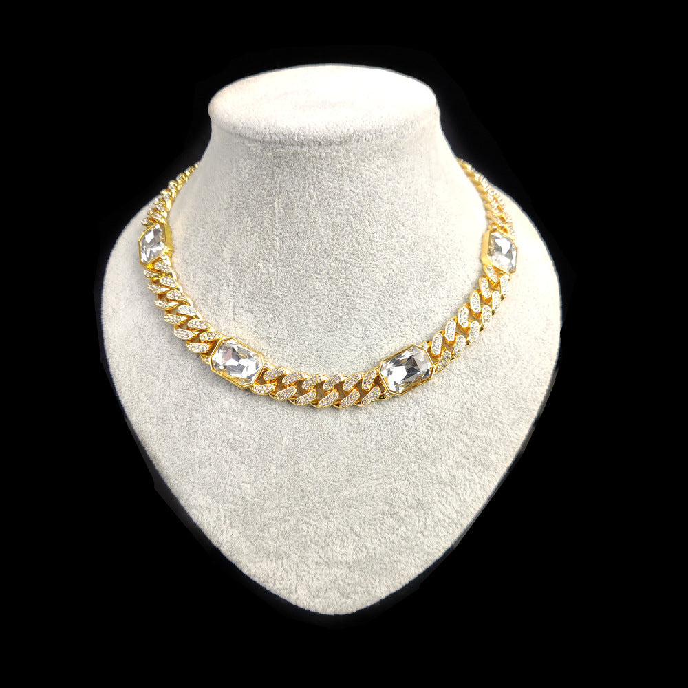 Gold chain necklace with clear stones on a white mannequin bust against a black background