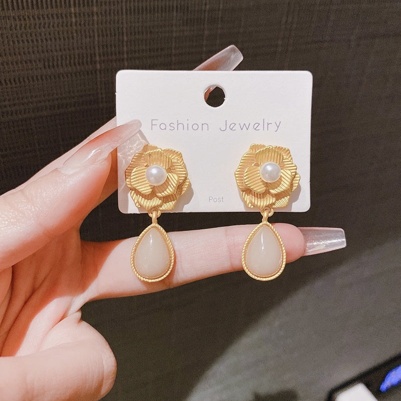 Gold and beige earrings on a 'Fashion Jewelry' card held by a hand.