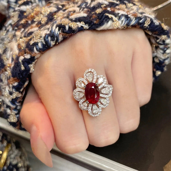 Close-up of a hand wearing a ring with a red gemstone and diamond-like accents.