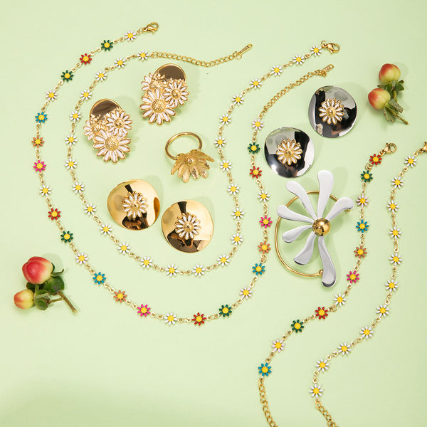Gold and silver jewelry set with floral designs on a light green background