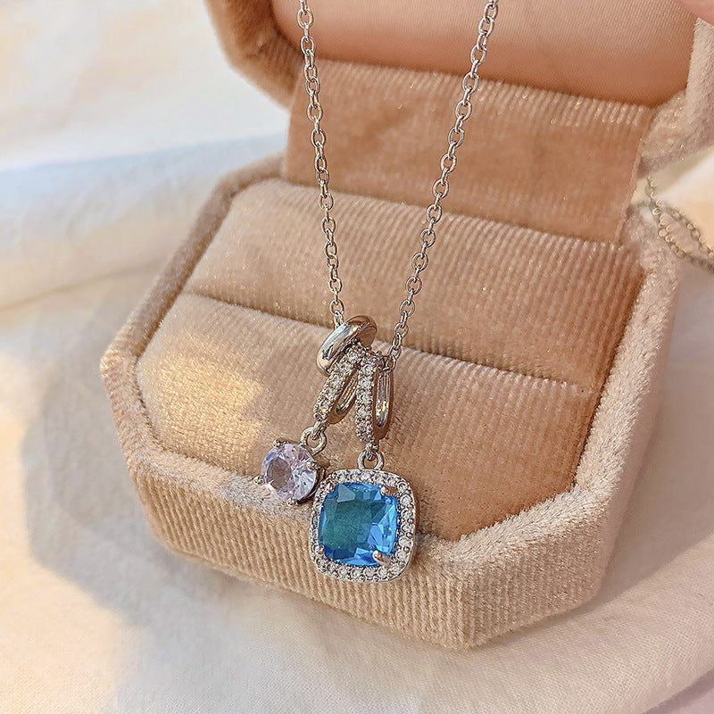 Necklace with a blue gemstone pendant on a beige jewelry box