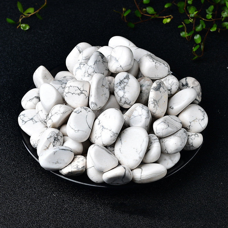 White marbled stones on a black surface with greenery in the background