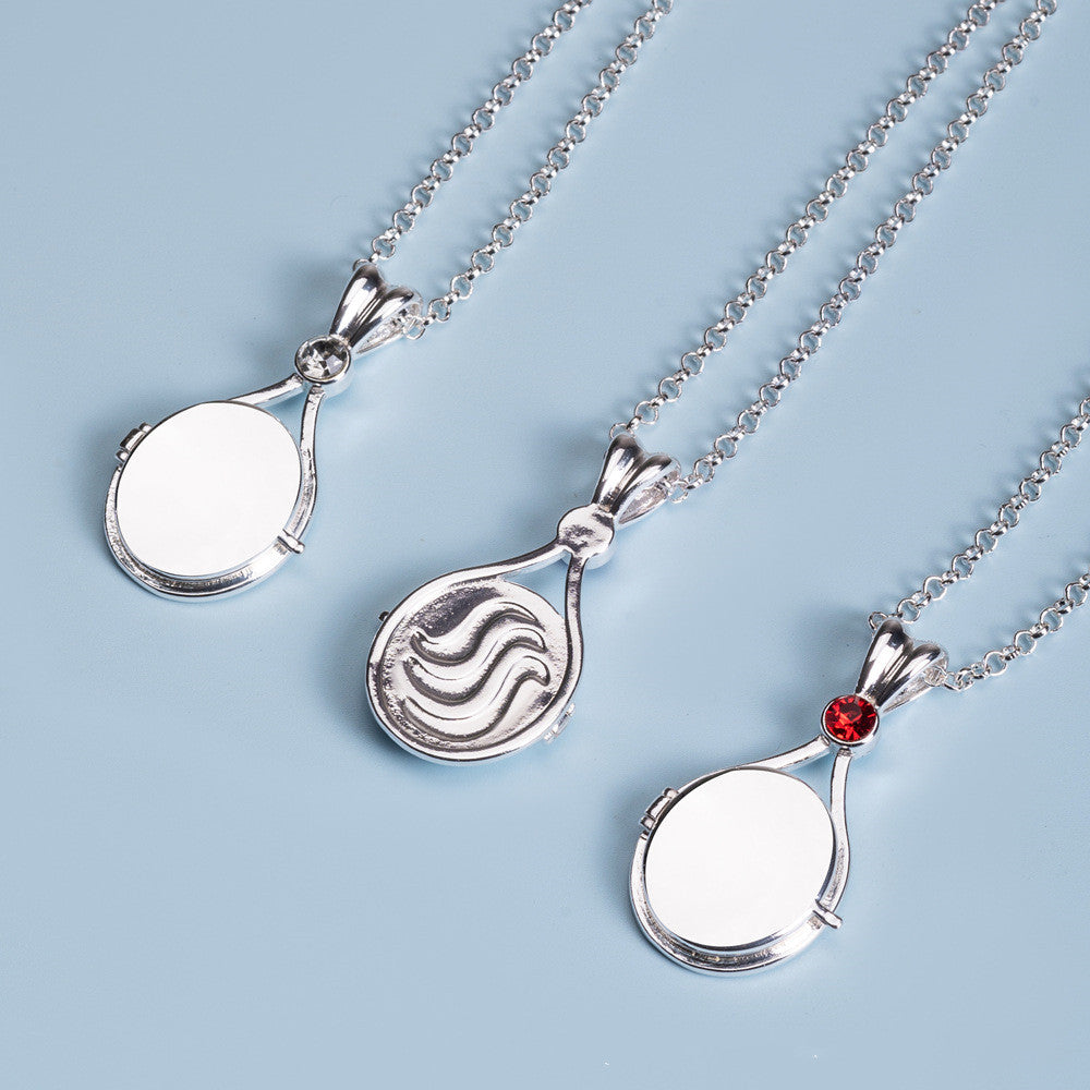 Three silver pendant necklaces on a light blue background