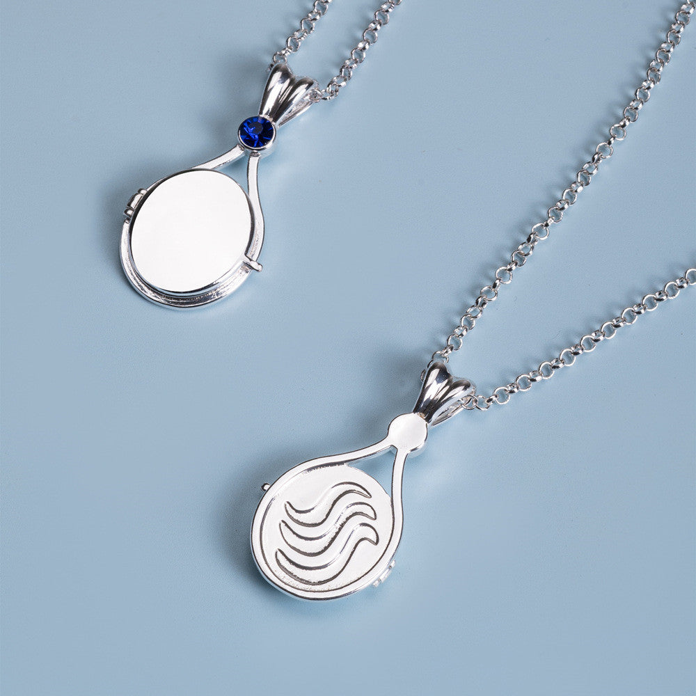 Silver necklaces with circular pendants on a light blue background