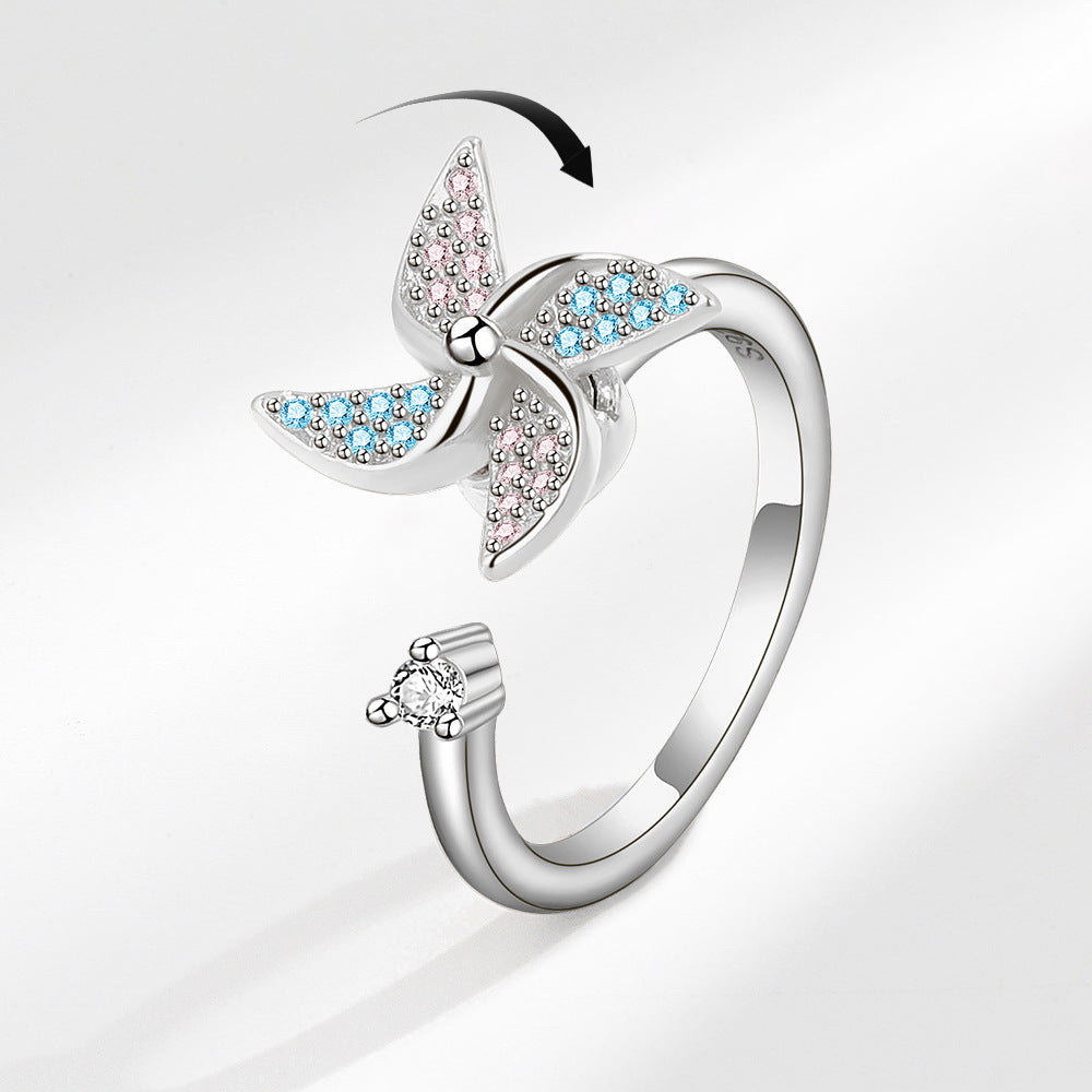 Butterfly-shaped ring with colorful gemstones on a light gray background