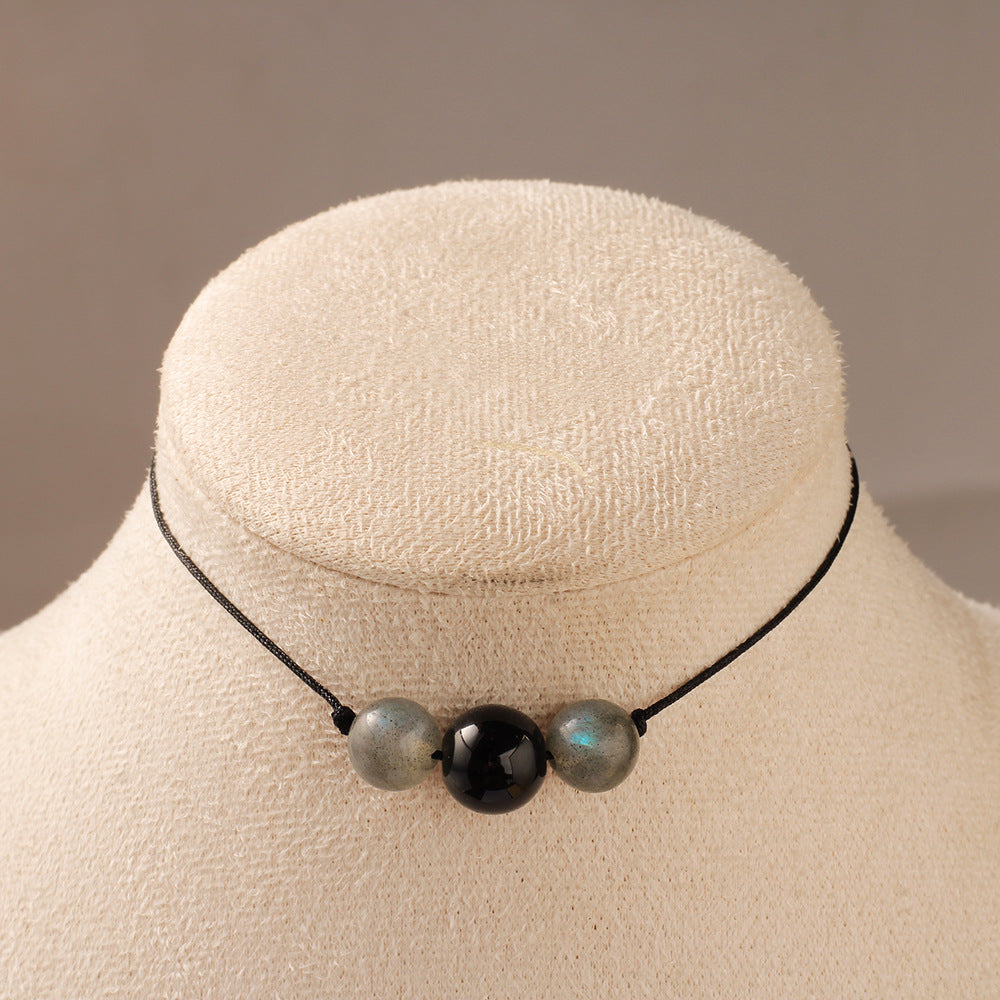 Necklace with three beads on a mannequin bust against a neutral background