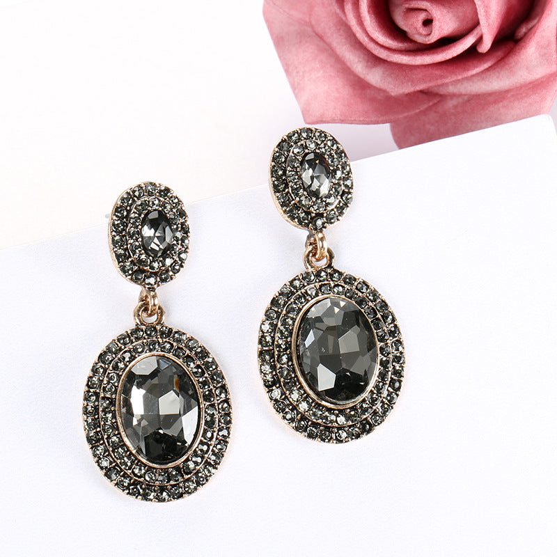Pair of ornate earrings with dark gemstones on a white background