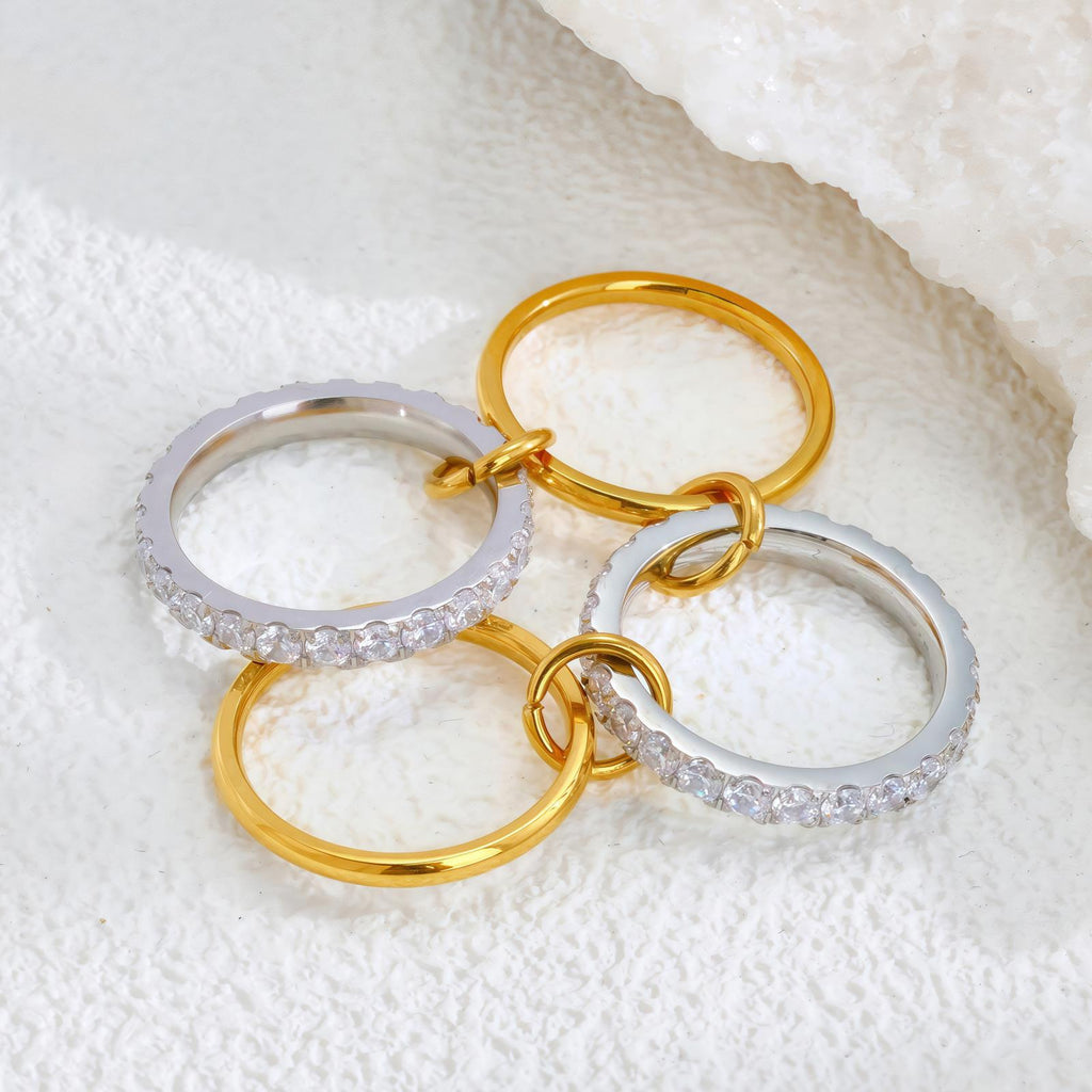 Three gold and silver rings with clear stones on a textured white surface