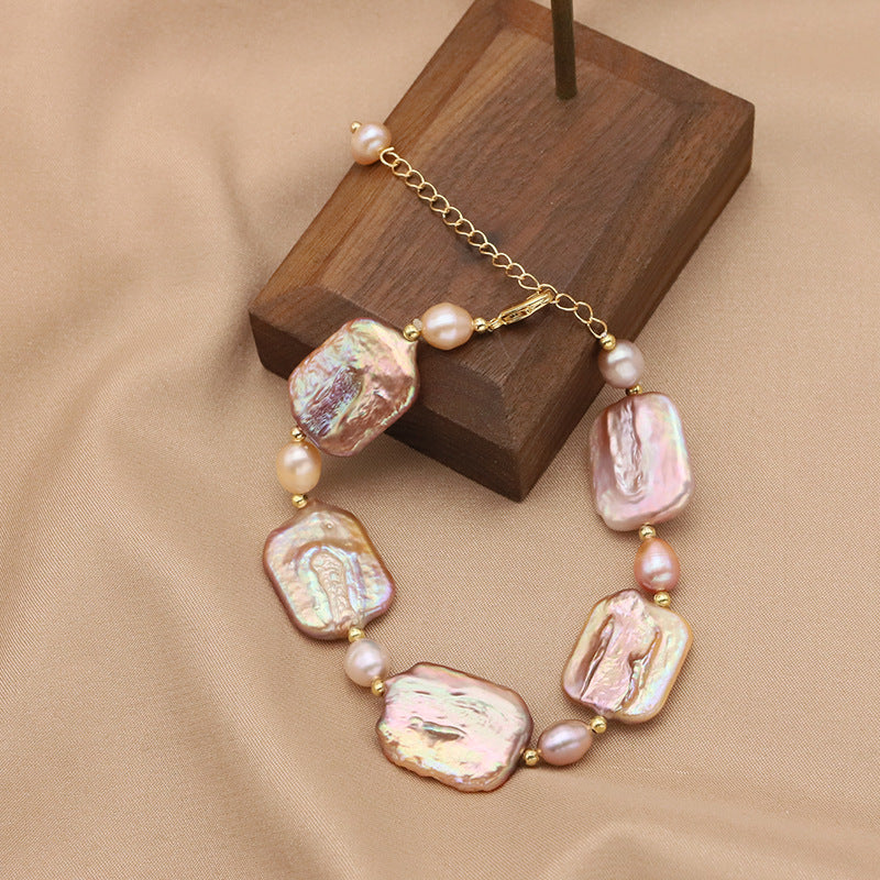 Necklace with large pink and gold beads on a wooden stand against a beige background