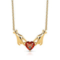 Gold necklace with a red heart-shaped gemstone on a white background