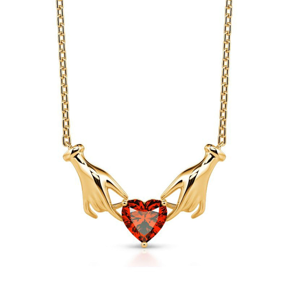 Gold necklace with a red heart-shaped gemstone on a white background