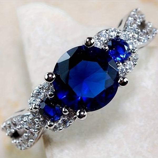 Ring with blue gemstone and diamond accents on a light background