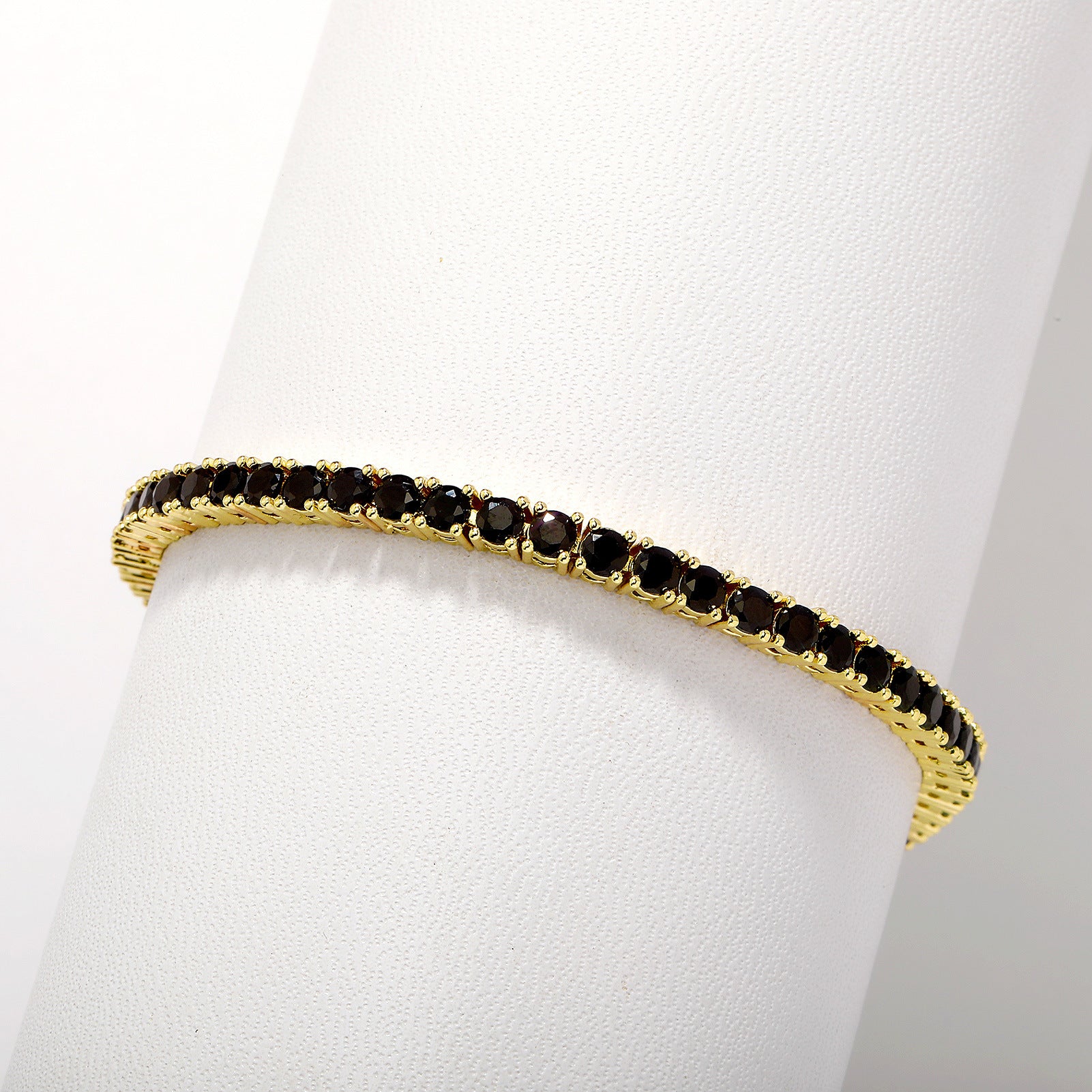 Gold bracelet with black stones on a white mannequin arm