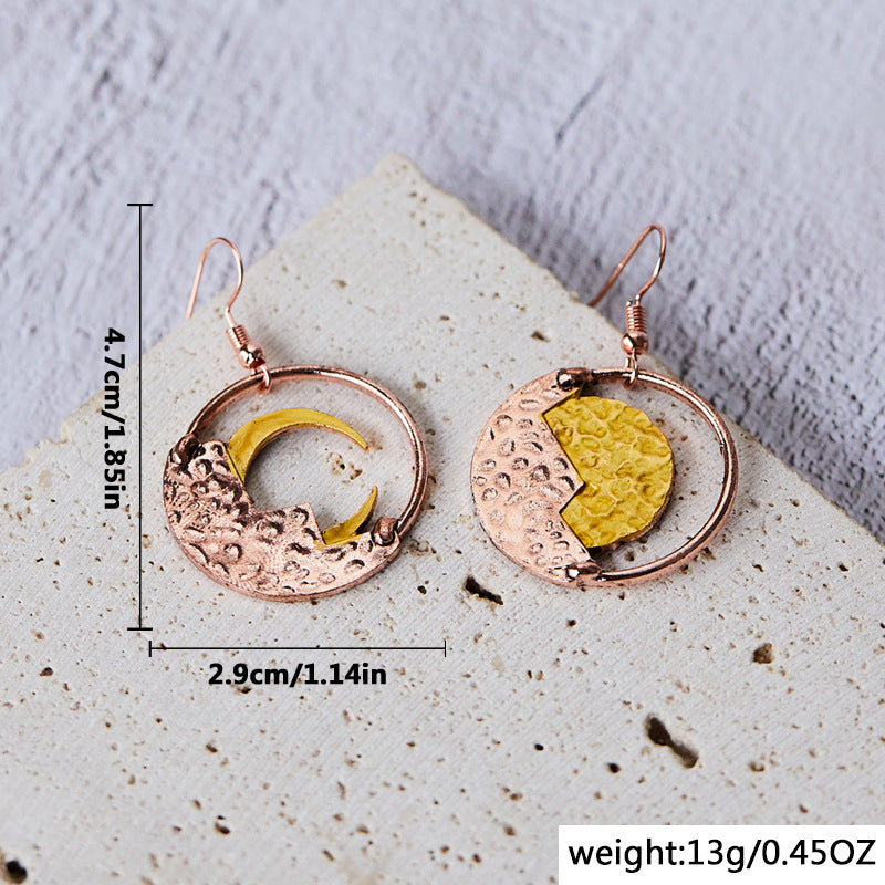 Pair of earrings with gold and copper design on a textured surface with measurements and weight information.