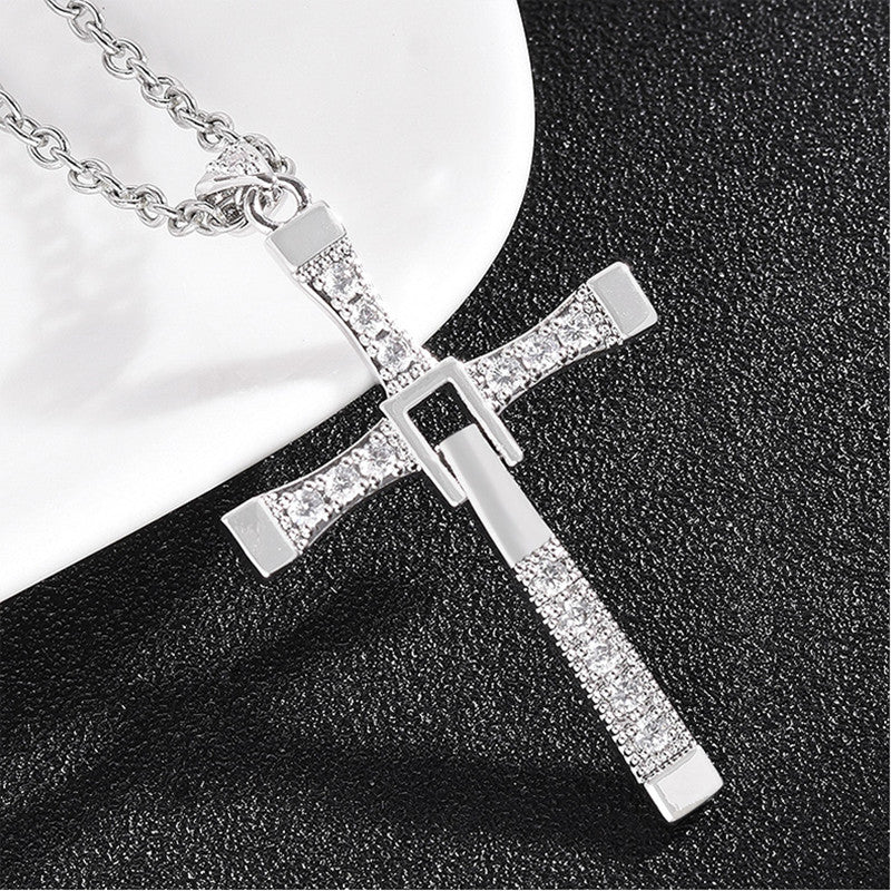 Silver cross pendant necklace with clear stones on a black and white background