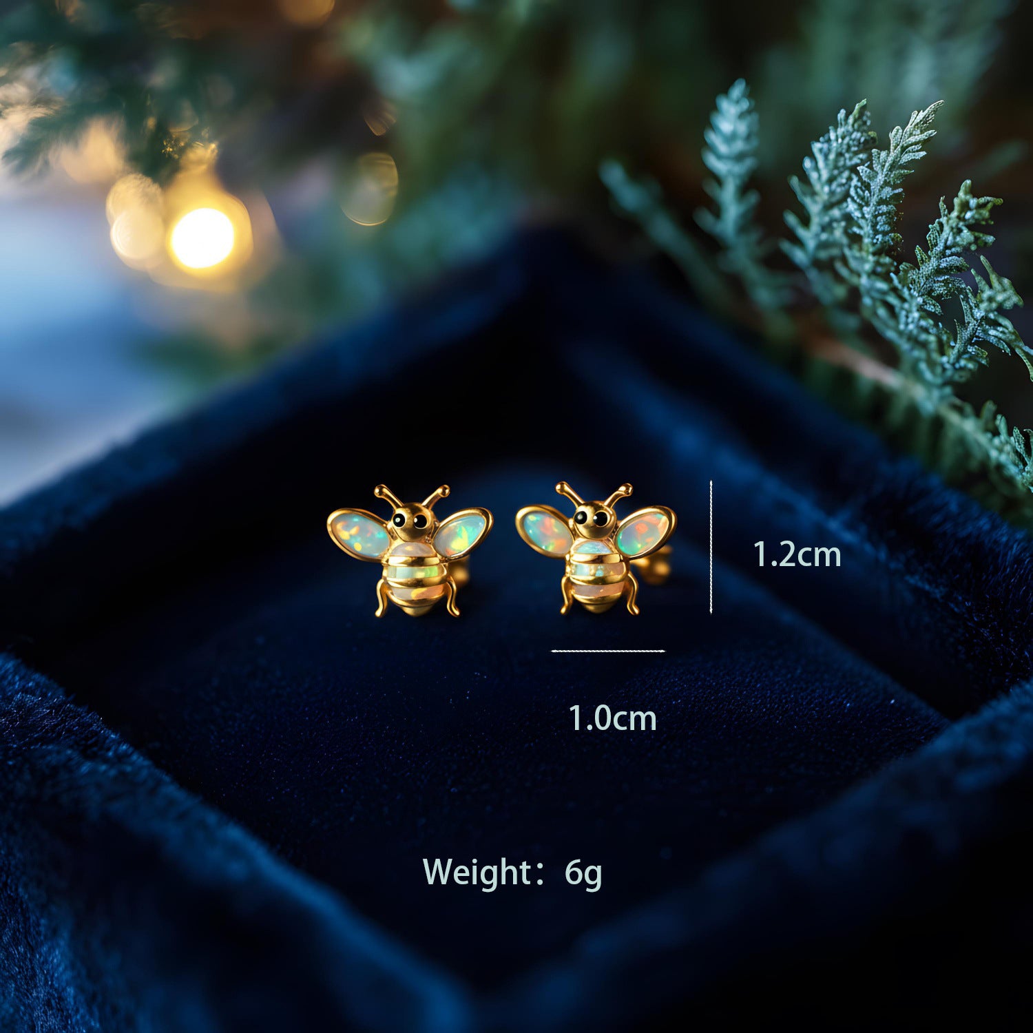 Gold bee-shaped earrings on a dark blue velvet surface with measurements and weight displayed.