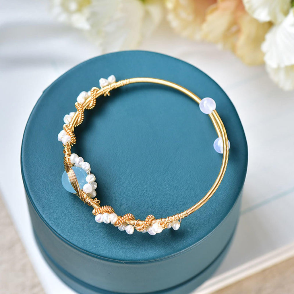 Gold hoop earrings with pearls on a teal jewelry box