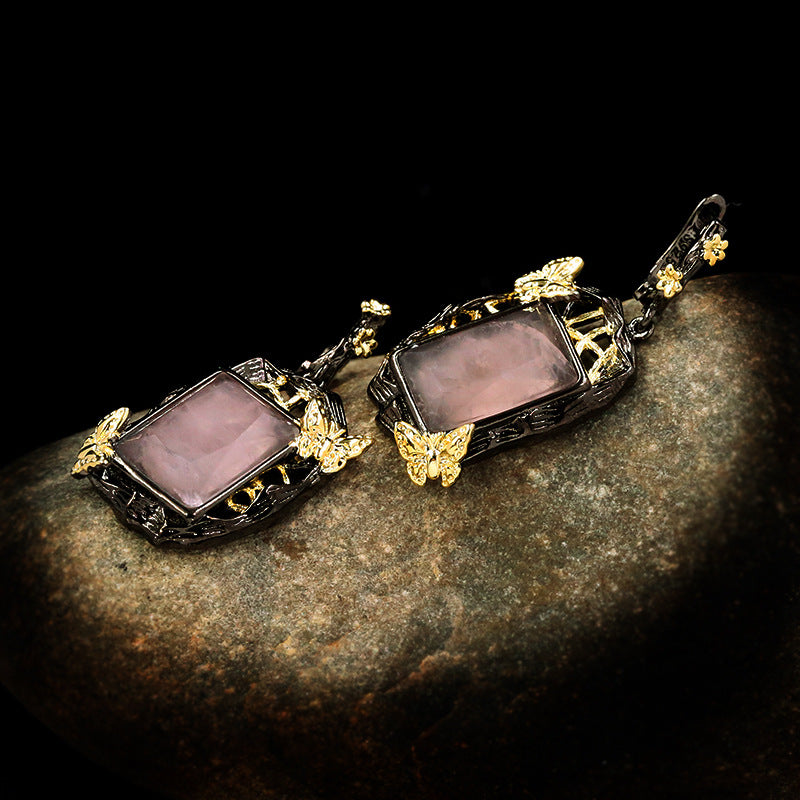 Pair of ornate earrings with purple stones on a dark surface