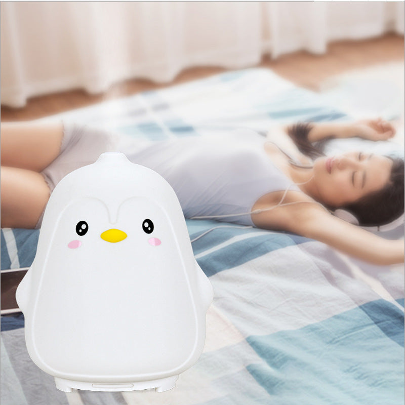 Cute penguin-shaped device on a bed with a person lying down
