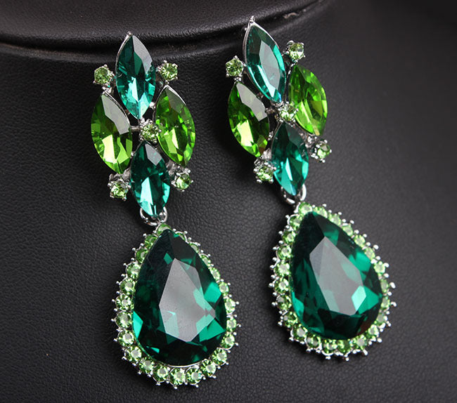Pair of green teardrop earrings on a dark background