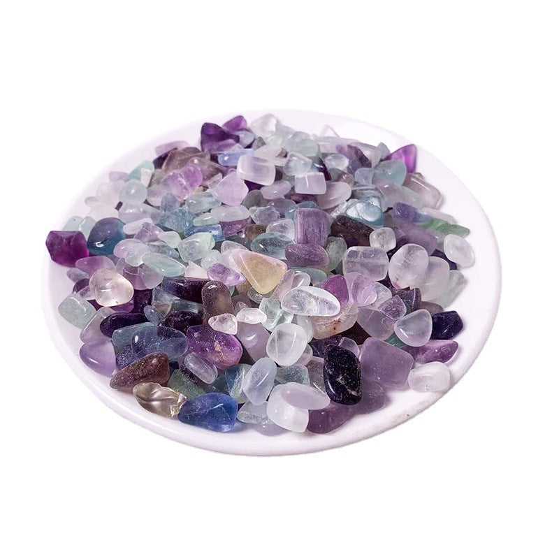 Assorted multicolored gemstones in a white dish on a white background